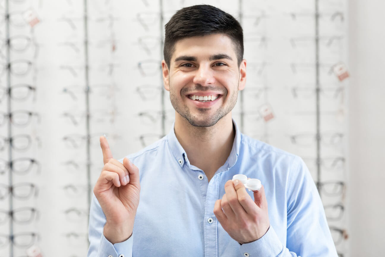 Men smiling while holding contact lens